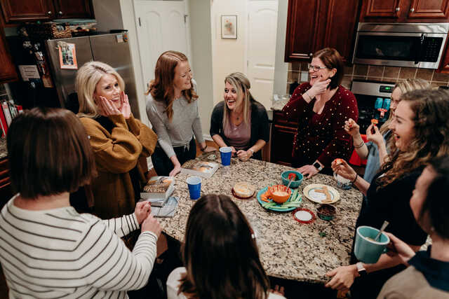 women laughing around a kitchen island during community group