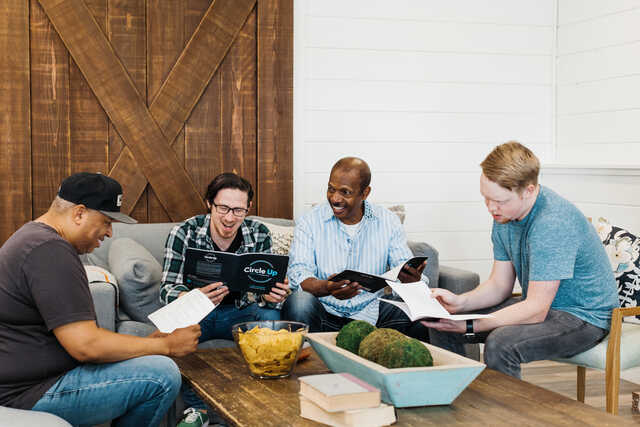 group of men meeting in a living room studying the bible together